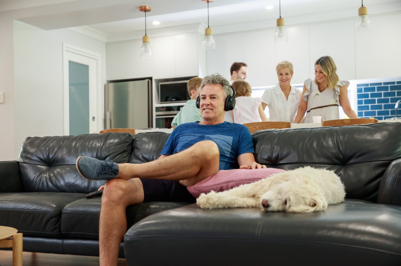 Man zit op zijn sofa met koptelefoon